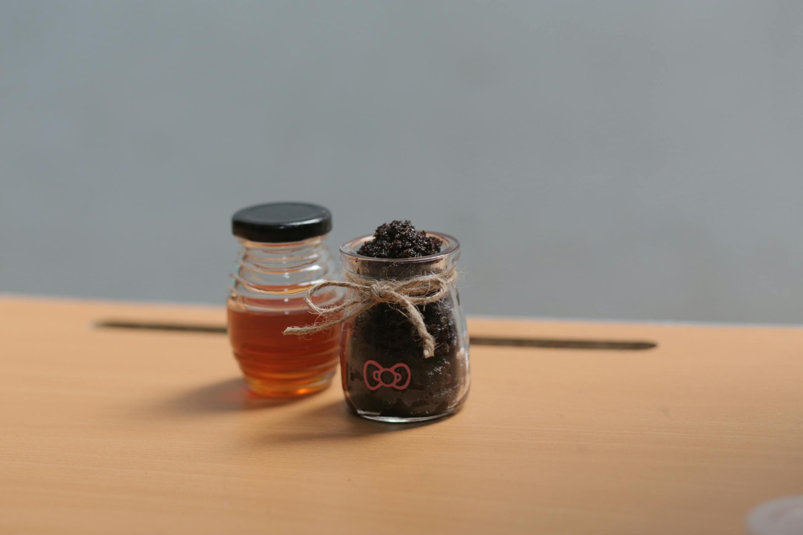 Glass jars with honey and a scrub on a wooden surface, perfect for health or spa themes.